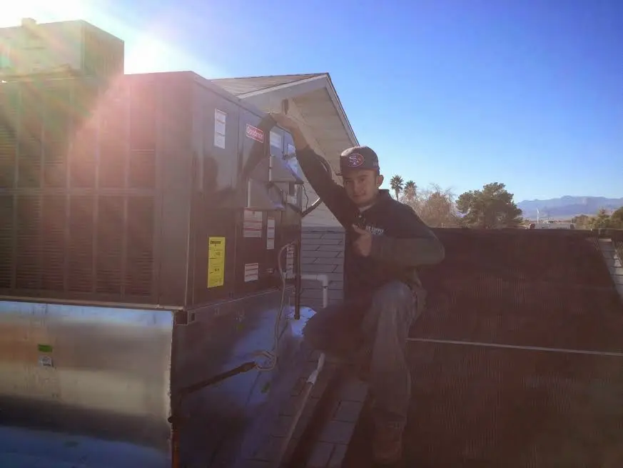 HVAC technician performing Air Duct Cleaning on a rooftop unit in Highlands